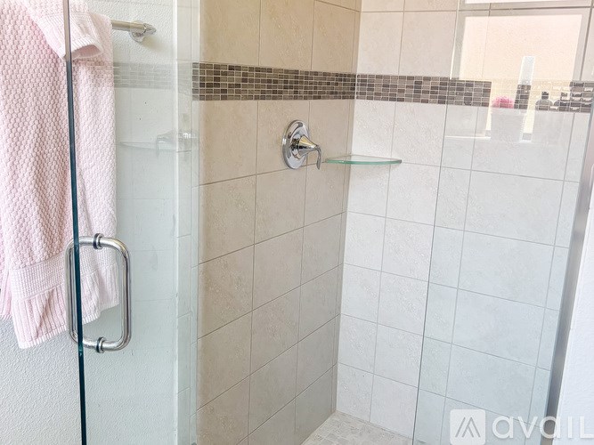 A bathroom with a shower and a pink towel hanging on the shower rod.