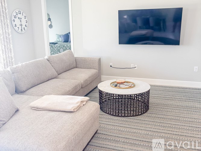 A living room with a grey couch and a round ottoman.