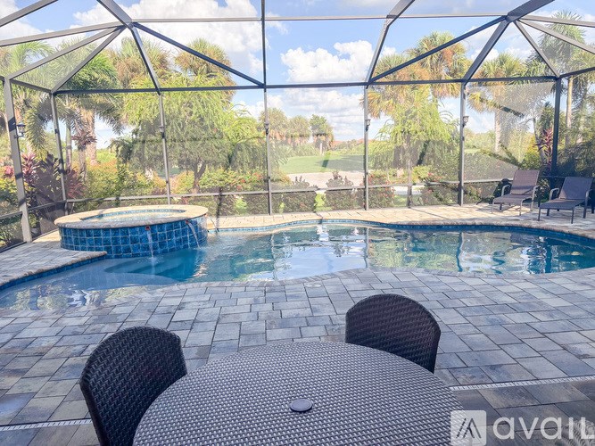 A patio with a table and chairs overlooking a pool.