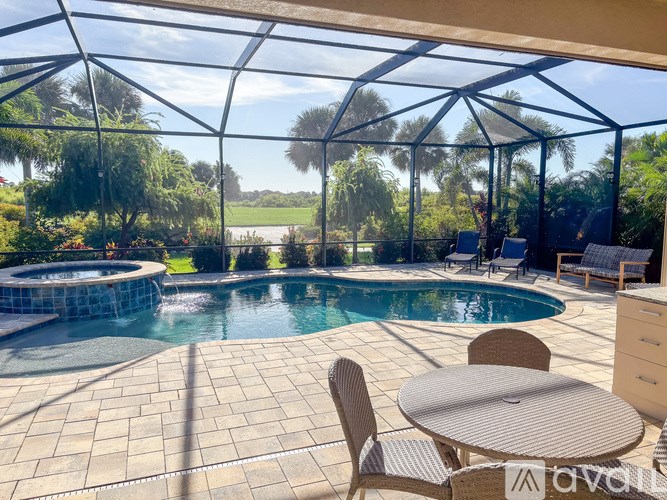 A patio with a table and chairs overlooking a pool.