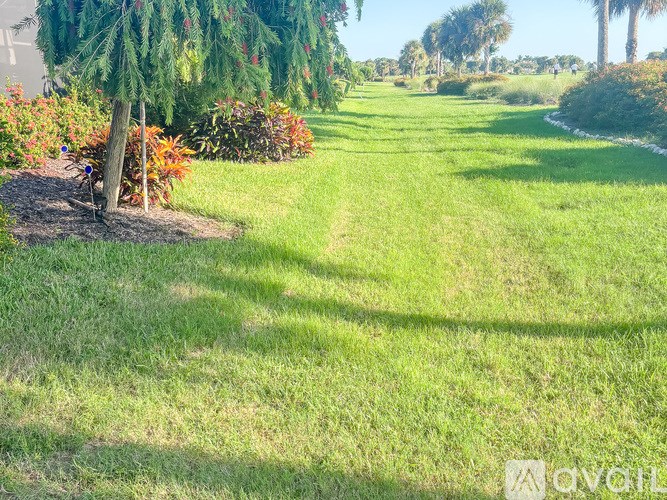 A well-maintained lawn with a small garden and trees in the background.