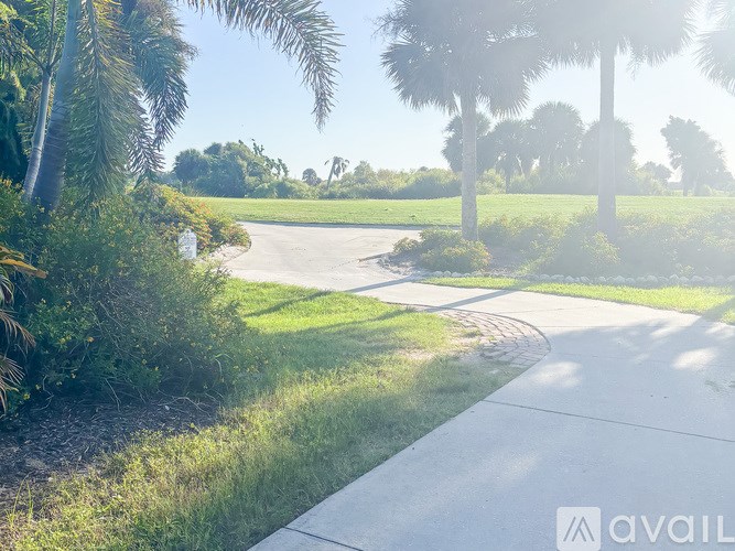 A pathway with a grassy area and palm trees in the background.