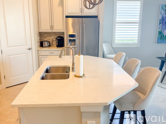 A kitchen with a white countertop and a stainless steel refrigerator.