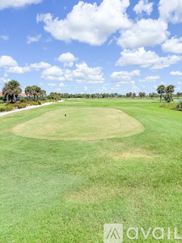 A golf course with a clear blue sky and a few clouds.