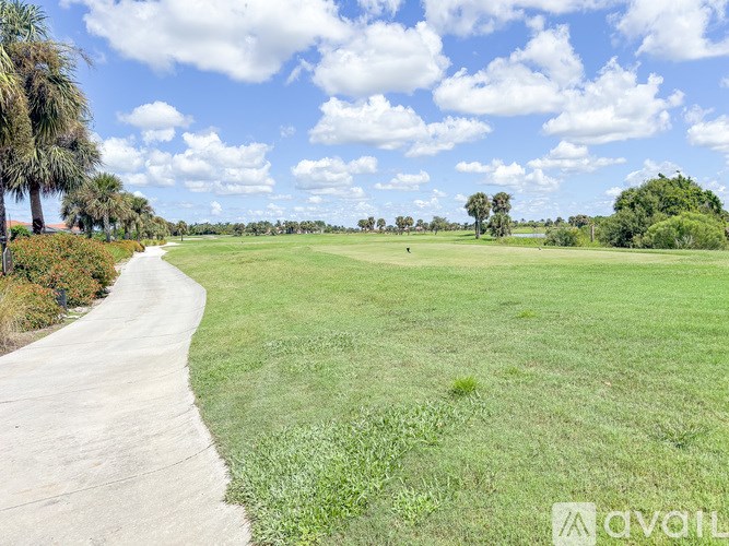 A pathway leads through a grassy field with trees in the distance.