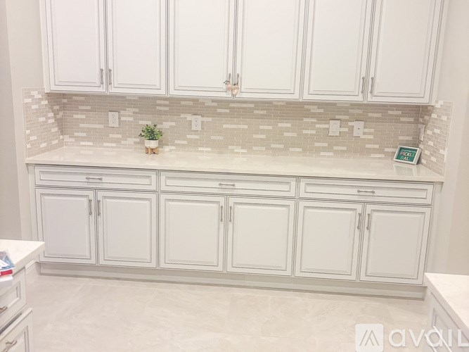 A kitchen with white cabinets and a tiled backsplash.