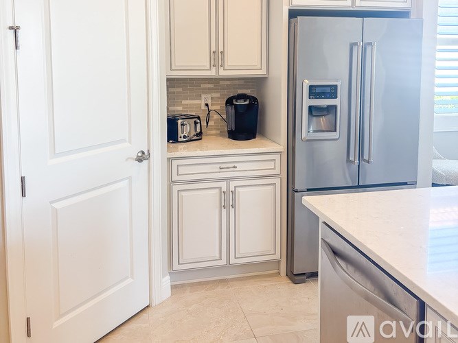 A kitchen with a refrigerator, toaster, and coffee maker.