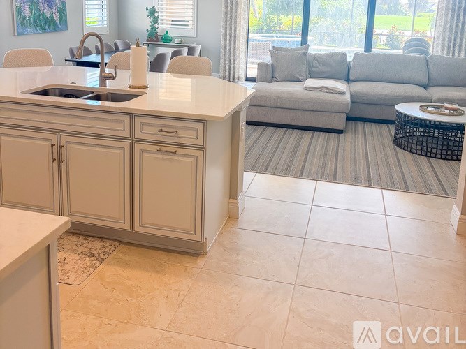 A kitchen with a sink, a counter, and a couch in the background.
