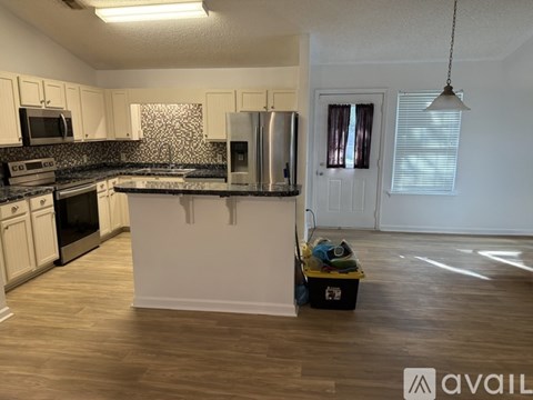 A kitchen with white cabinets and a black and white patterned backsplash.