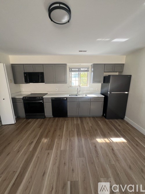 A kitchen with wooden floors and black appliances.