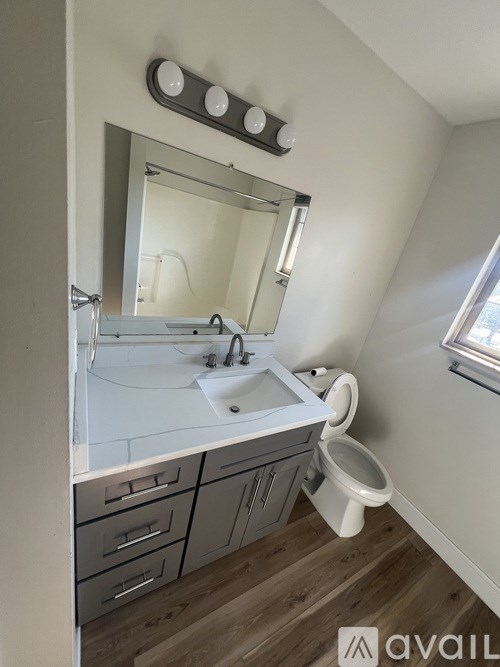 A bathroom with a sink, toilet, and mirror.