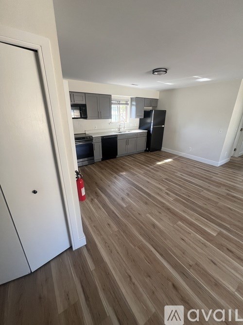 A kitchen with a black fridge and wooden floors.