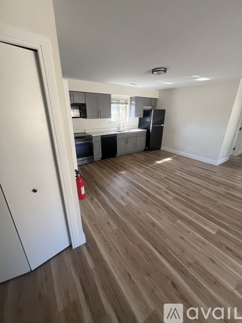 A kitchen with a black fridge and wooden floors.