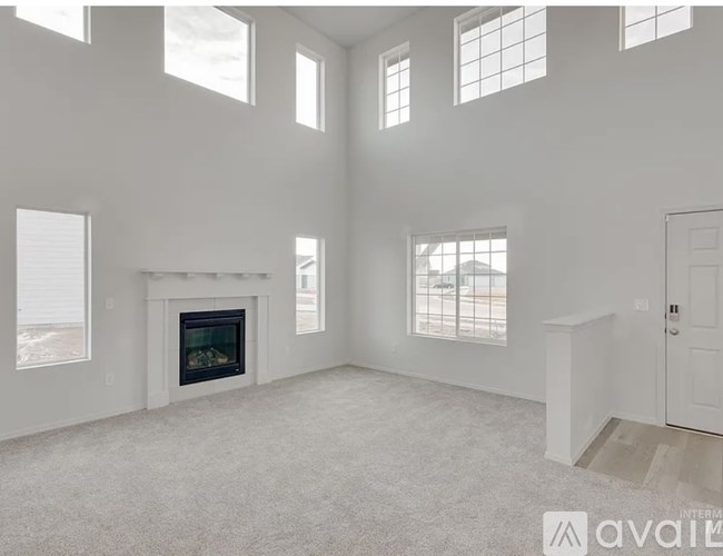 A large, empty room with a fireplace and carpeted floor.