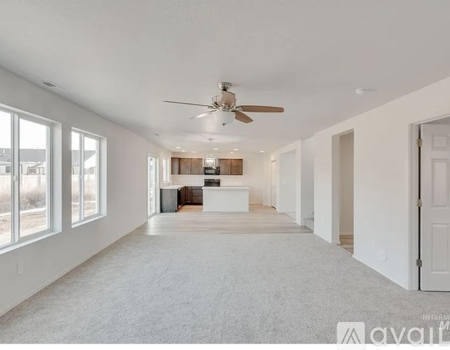 A spacious, empty room with a ceiling fan and large windows.