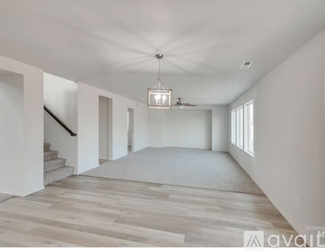 A spacious room with a staircase and a ceiling fan.