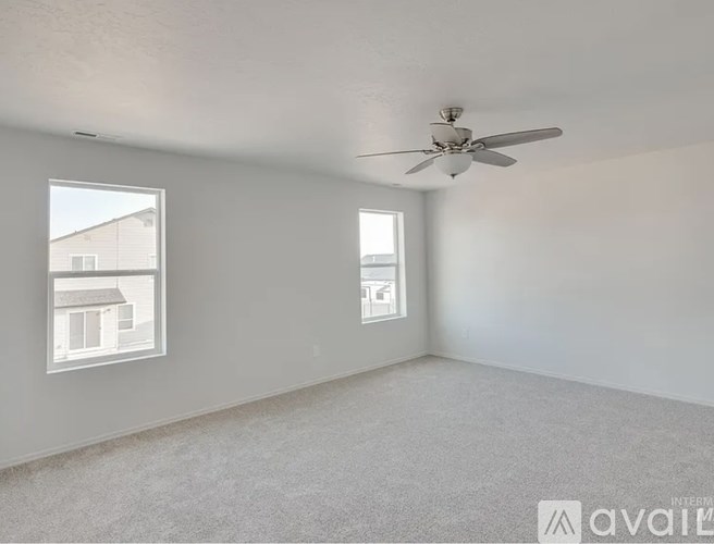 A room with a ceiling fan and two windows.