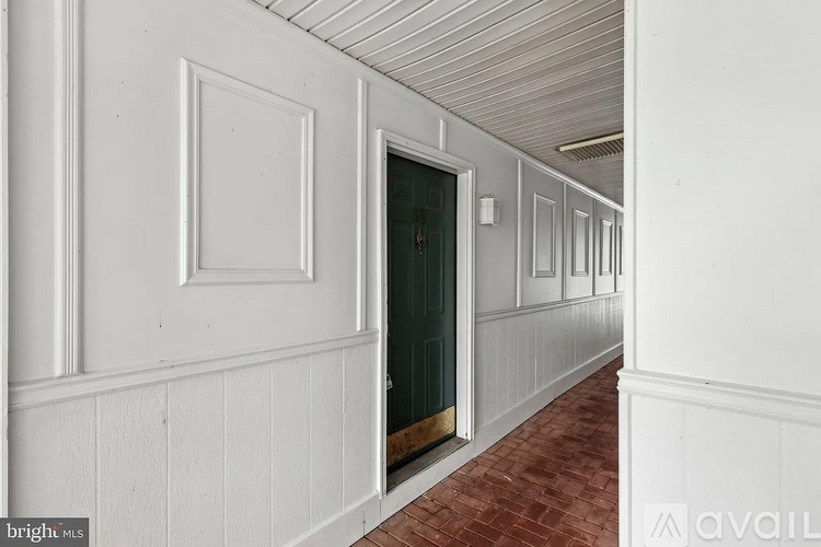 A hallway with white walls and a red brick floor.