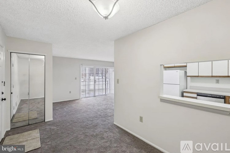 A spacious room with a carpeted floor and a window with blinds.