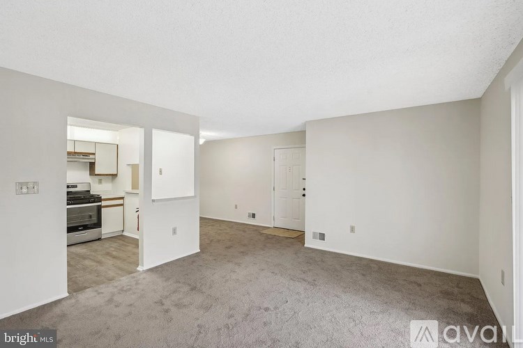 A spacious living room with a kitchen in the background.