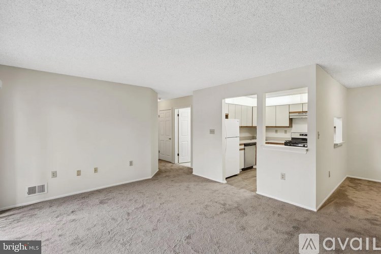 A spacious, empty room with a kitchenette in the background.