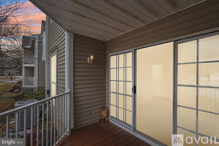 A balcony with a glass door and a small table with a chair.