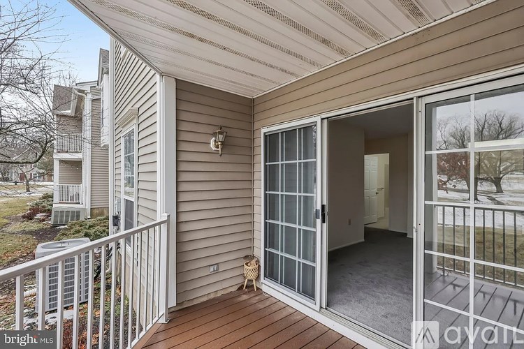 A balcony with a glass door leading to a room.