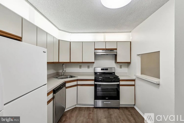 A kitchen with white cabinets and a stainless steel dishwasher and oven.