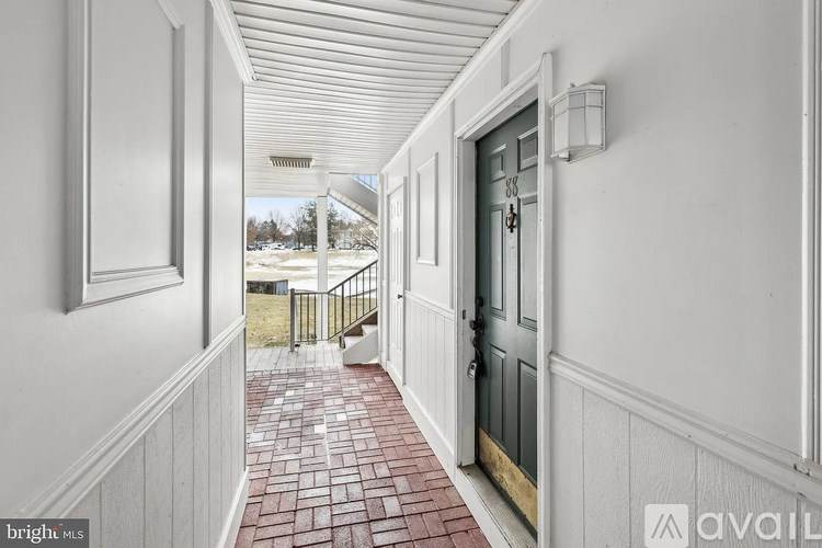 A hallway with a black door and a brick floor.