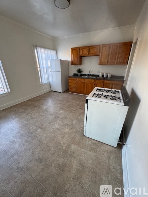 A kitchen with a white stove top oven and wooden cabinets.
