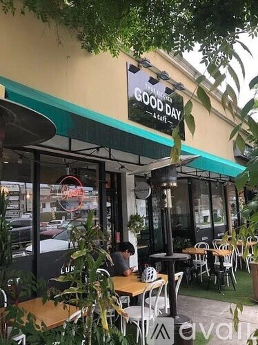 A cafe named Good Day is seen with a person sitting inside.