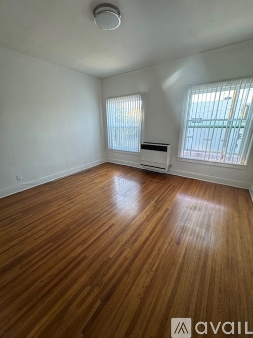 A room with wooden flooring and a window with blinds.