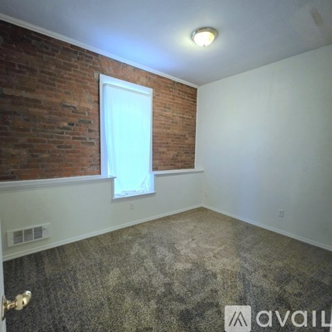 A room with a carpeted floor and a window with a red curtain.