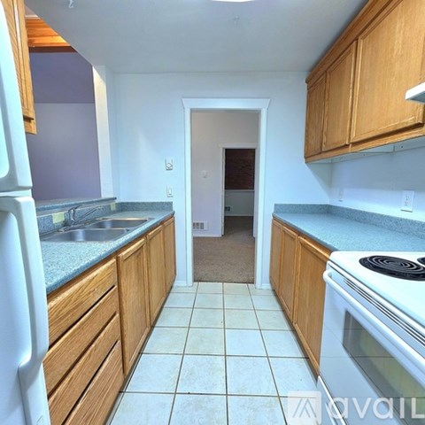 A kitchen with white appliances and wooden cabinets.