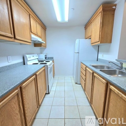 A kitchen with wooden cabinets and a white stove top oven.