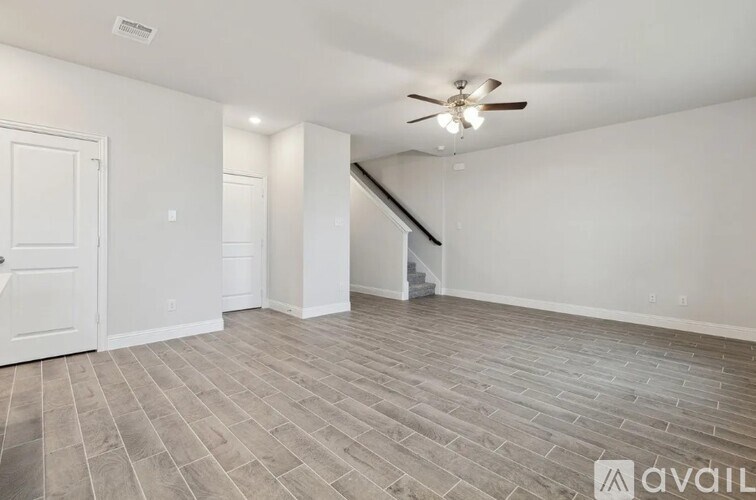 A room with a ceiling fan and a wooden floor.
