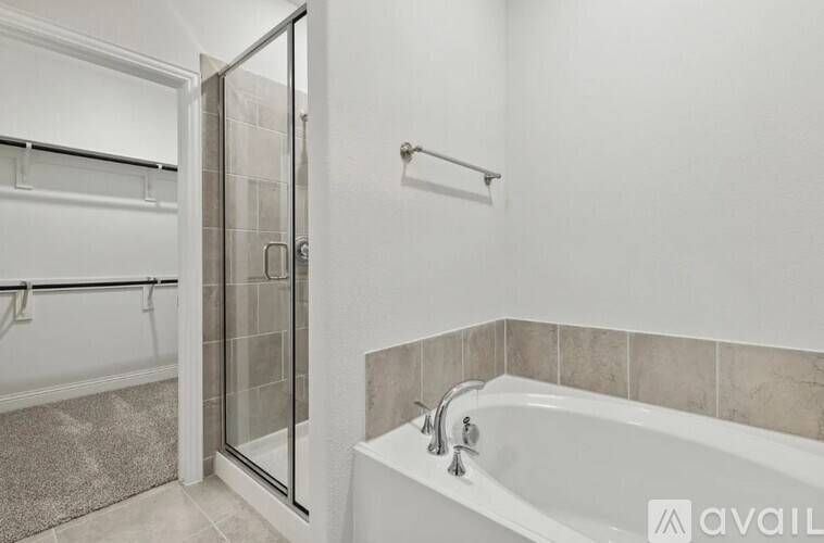 A bathroom with a white tub and a glass shower door.