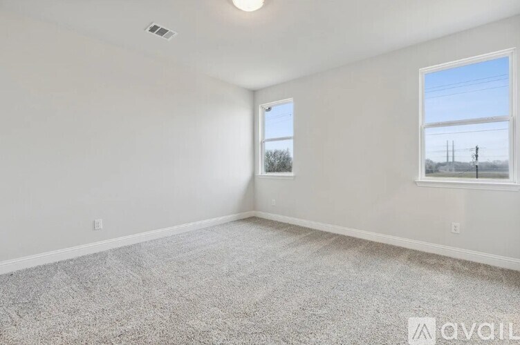 A room with a carpeted floor and two windows.