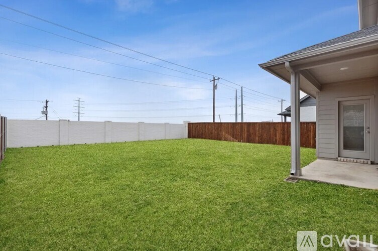 A backyard with a wooden fence and a house with a small porch.
