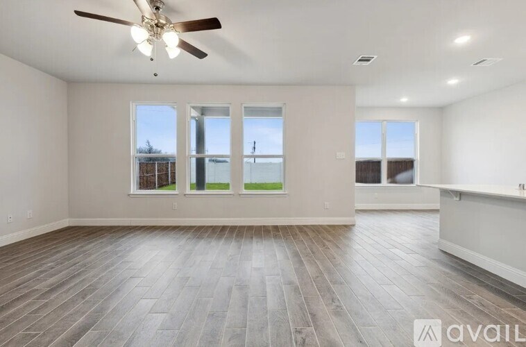 A spacious room with a ceiling fan and wooden flooring.
