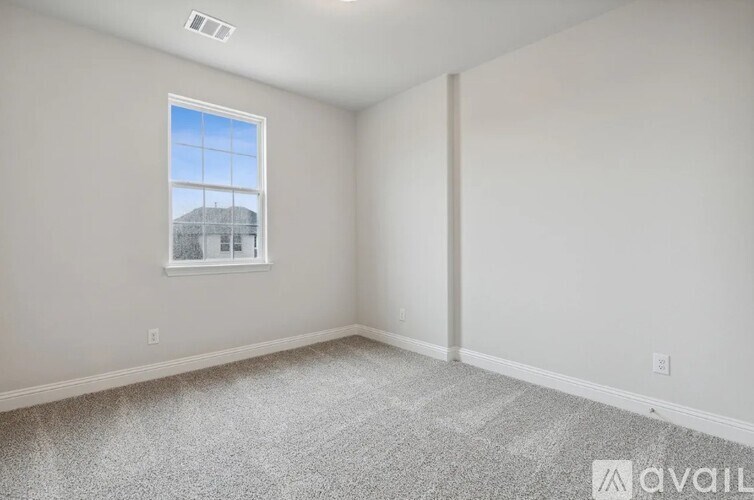 A room with a window and a carpeted floor.