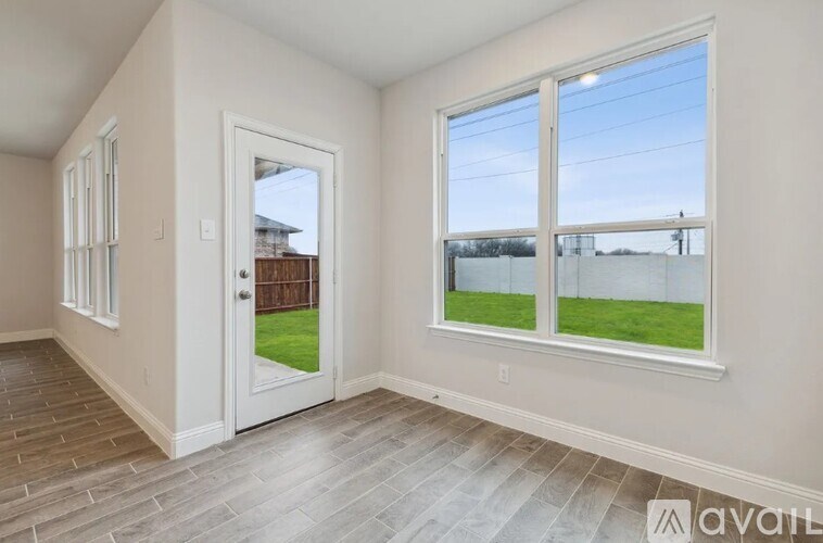 A room with a large window and a door leading to a backyard.
