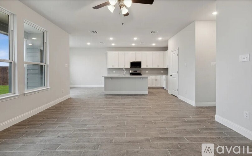 A spacious kitchen and living room with a ceiling fan and lighting.