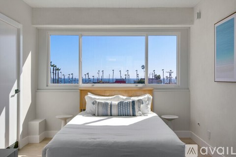 A bedroom with a large bed and a view of the beach through the window.