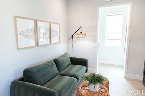 A living room with a green couch and a small table with a plant on it.