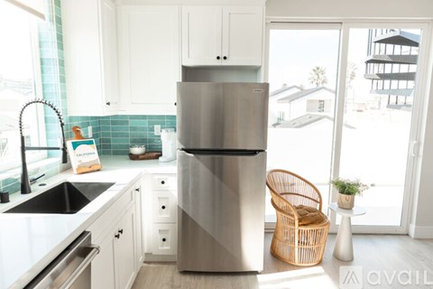 A modern kitchen with a stainless steel refrigerator and white cabinets.