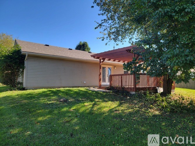 A house with a brown roof and a white garage door is surrounded by a grassy lawn and trees.