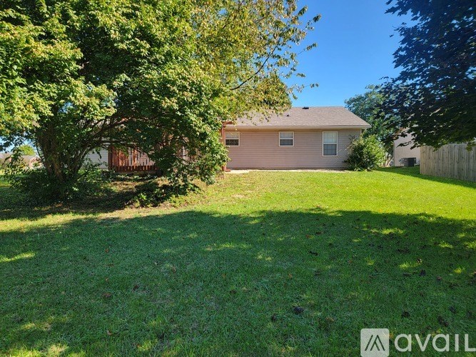 A house with a fence and a tree in front of it.