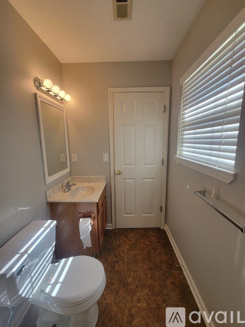 A bathroom with a toilet, sink, and mirror.