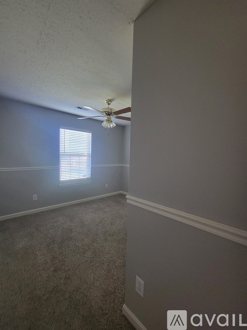 A room with a ceiling fan and a window with blinds.